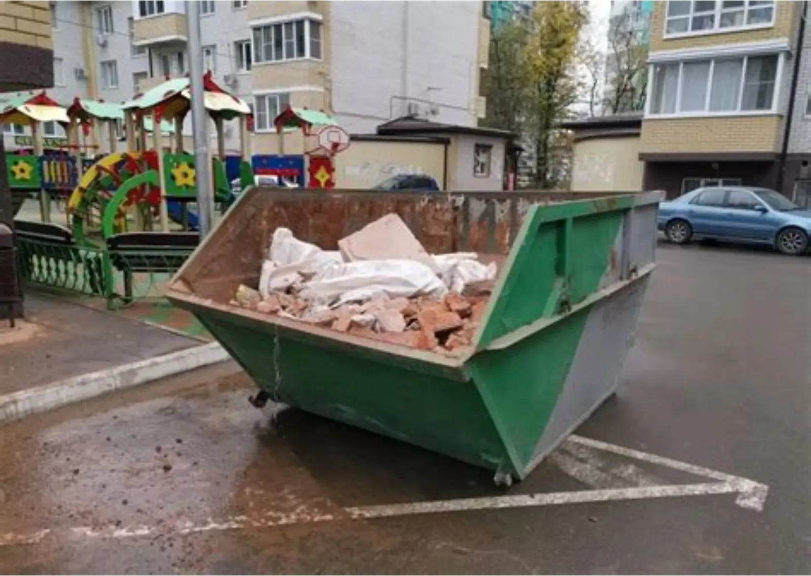 Бункер-накопитель во дворе, загруженный строительным мусором